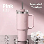 A pink 1.2L insulated tumbler with a handle, clear lid, and metal straw, shown with water droplets on a pink background.