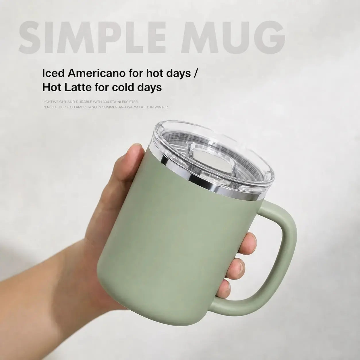 A hand holds a matte sage green insulated mug with a clear lid and silver rim. The background is a light gray textured wall with text overlays reading 'SIMPLE MUG' and 'Iced Americano for hot days / Hot Latte for cold days'.