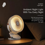 A small white fan with warm amber LED light glowing from the front, shown on a wooden table in a dim bedroom setting next to a pillow. White text on the right reads 'Ambient night light With You Every Night' with additional descriptive copy.