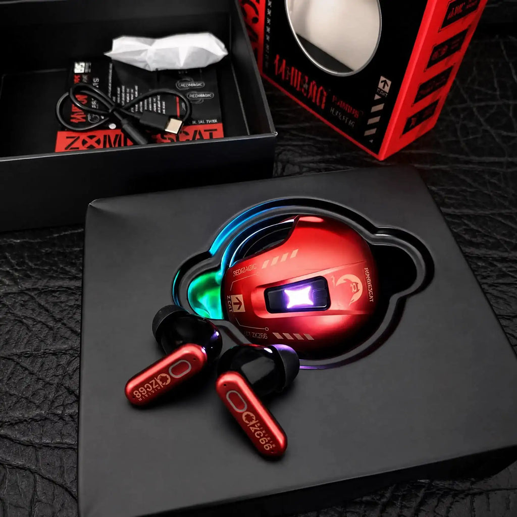 Red and black true wireless earbuds with a matching red wireless gaming mouse, displayed in their black retail packaging on a textured black surface.