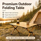 A premium folding camping table made of light wood slats with a black metal frame, shown set up outdoors next to a tent and a lantern. The image features promotional text highlighting its features and dimensions.